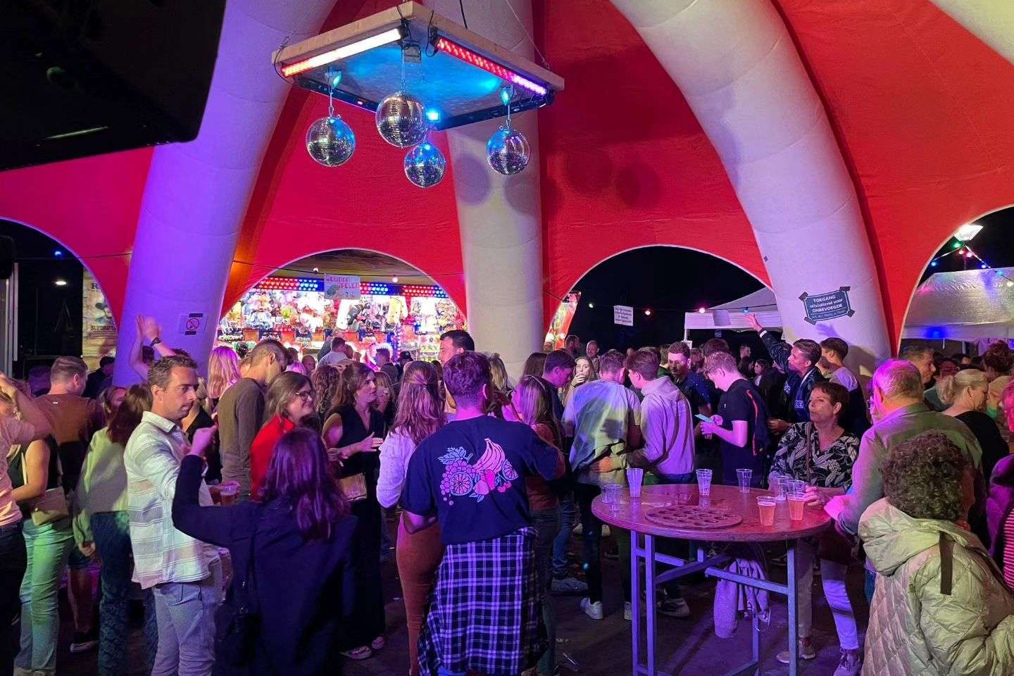 Volle feesttent met discobal en roze verlichting