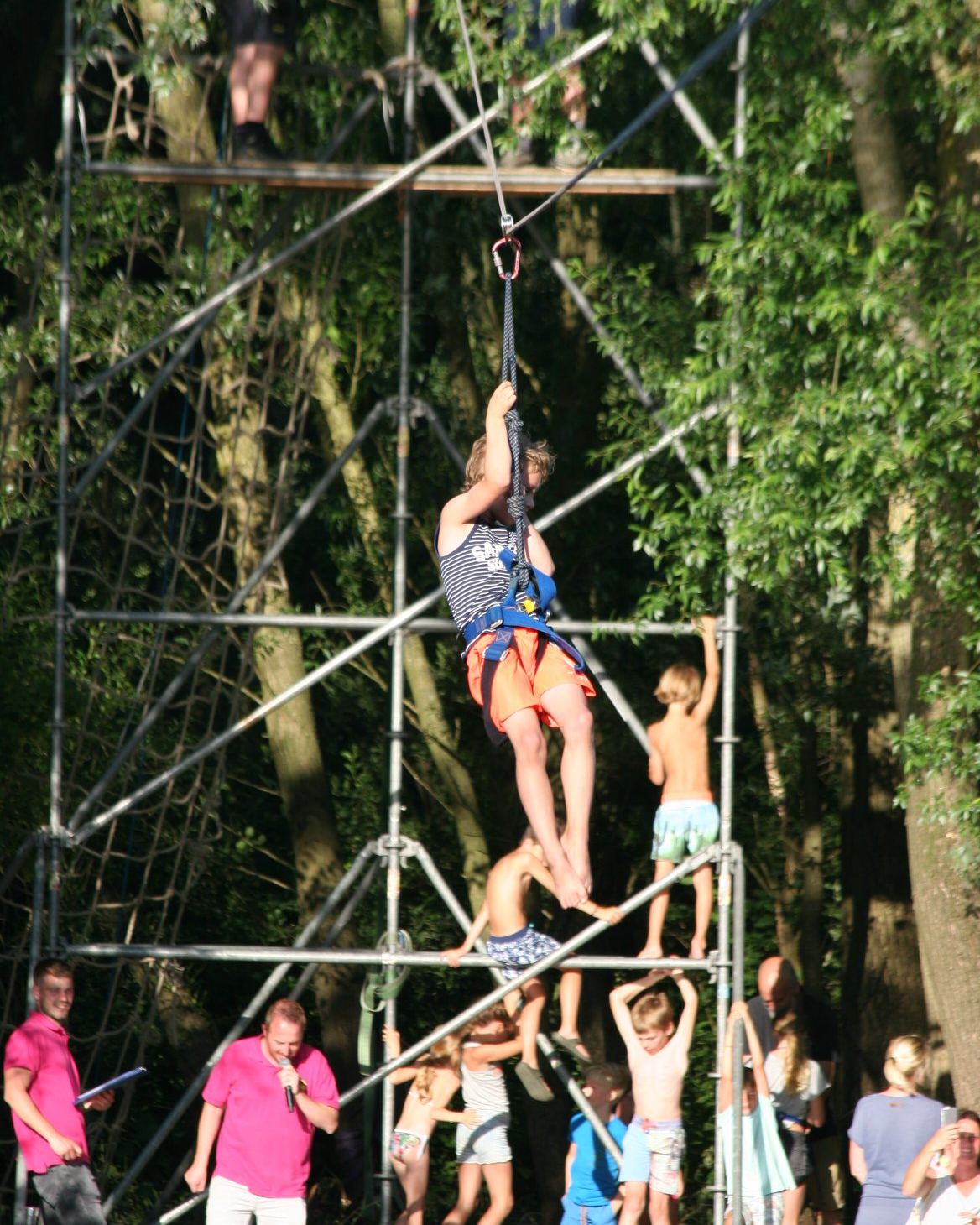 Kinderen klimmen in een klimtoren tussen de bomen
