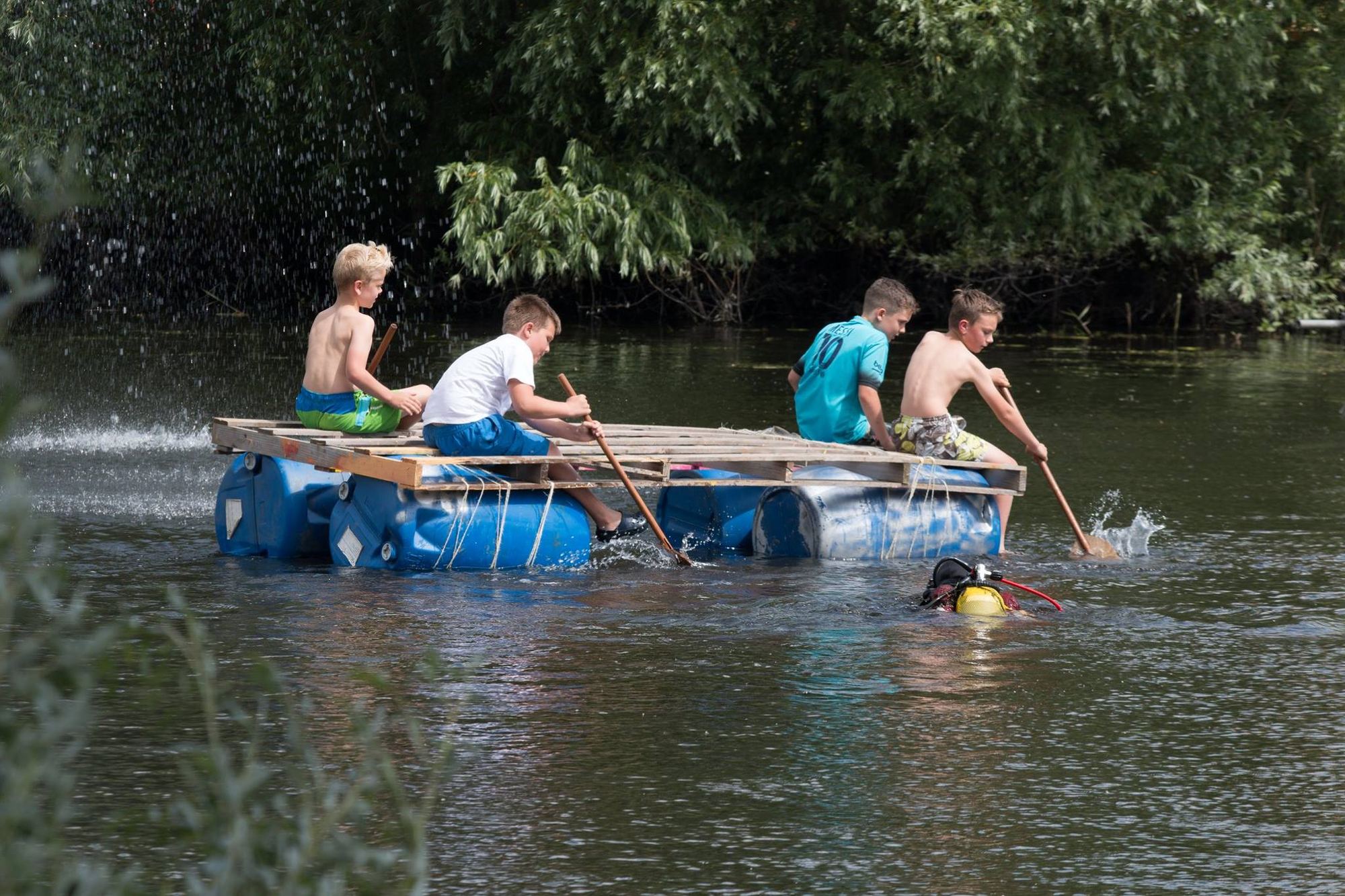 Kinderen varen op een zelfgebouwd vlot bij het Tobbedansen